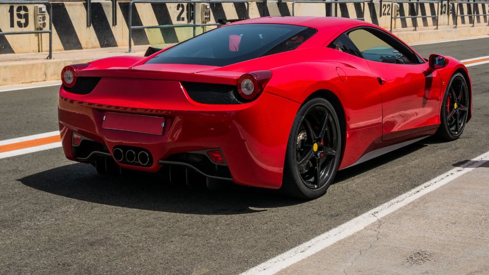 A Ferrari 458 Italia hátsó nézete, élénk piros színben, versenypályán.