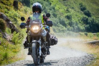 Motorkerékpáros terepen, porfelhőt kavarva halad a végsebesség-teszt során.