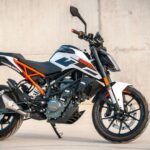 Egy stílusos motorkerékpár, fekete-fehér színkombinációval és narancssárga részletekkel.