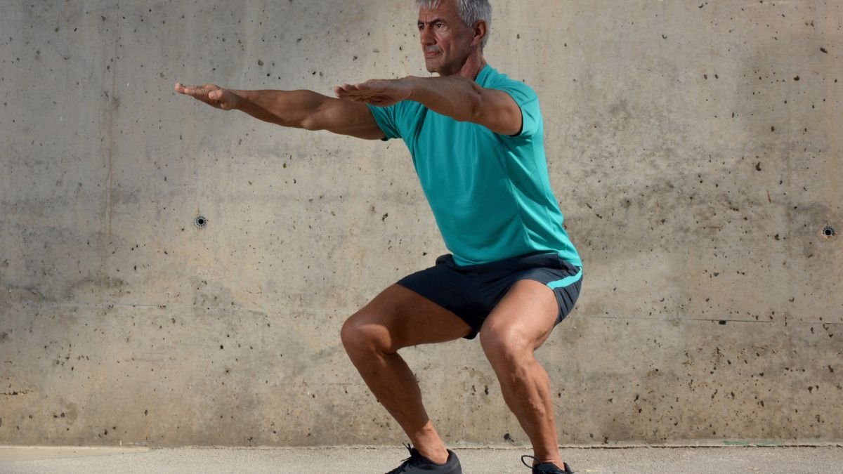 Egy férfi guggoló pozícióban, sportos ruházatban, edzés közben.