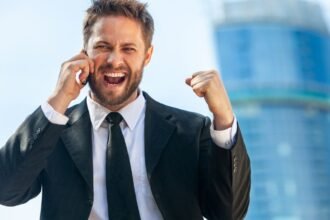 Sikeres férfi telefonál, izgalommal ünnepli győzelmét.